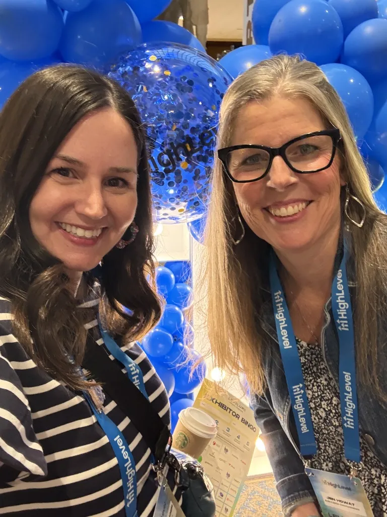 Erica Bollinger and a friend smiling in front of blue HighLevel balloons at LevelUp 2026