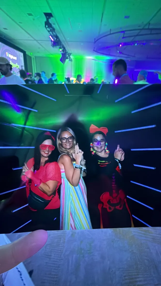 Erica and friends posing in a neon-lit photo booth at a LevelUp 2026 evening party